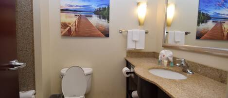 A bathroom with a toilet, sink, and two paintings on the wall.