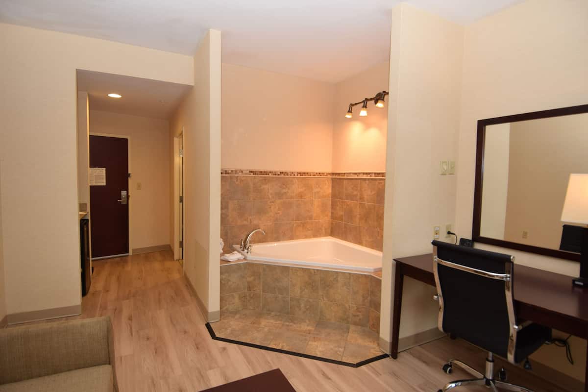 Een moderne badkamer met een bad, een douche, een wastafel met spiegel en een houten vloer.