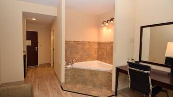 Un baño moderno con bañera, ducha, tocador con espejo y suelo de madera.