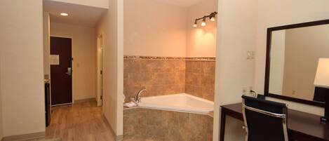 A modern bathroom with a bathtub, a shower, a vanity with a mirror, and a wooden floor.