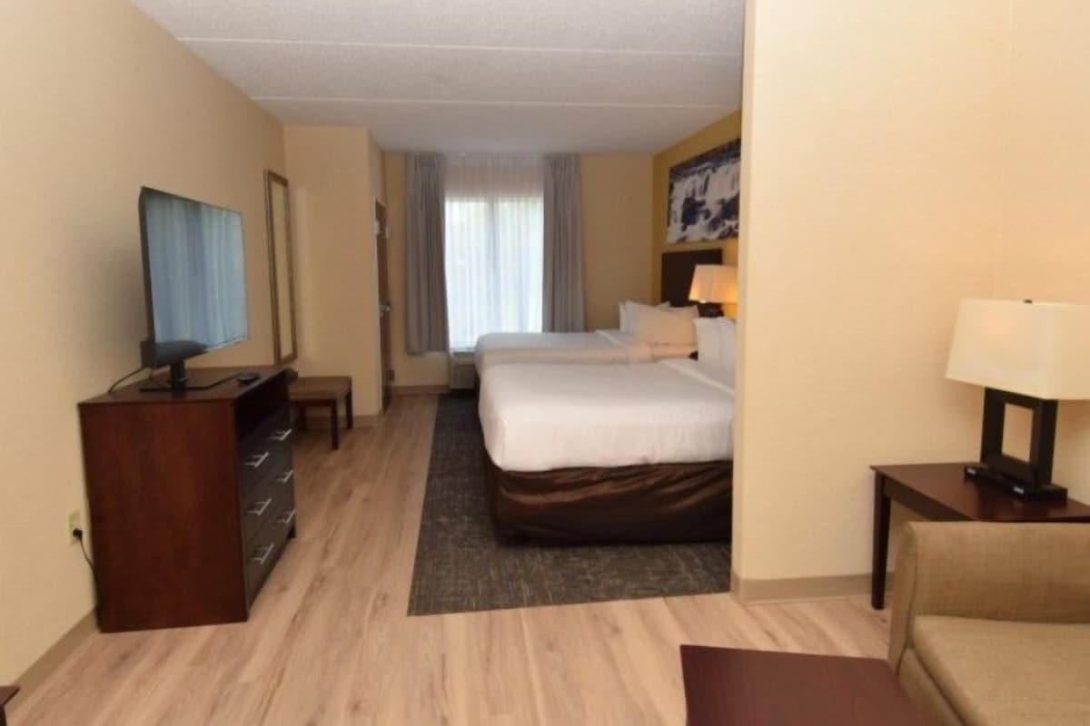 Une chambre d’hôtel avec un lit, un bureau, une télévision et une lampe.