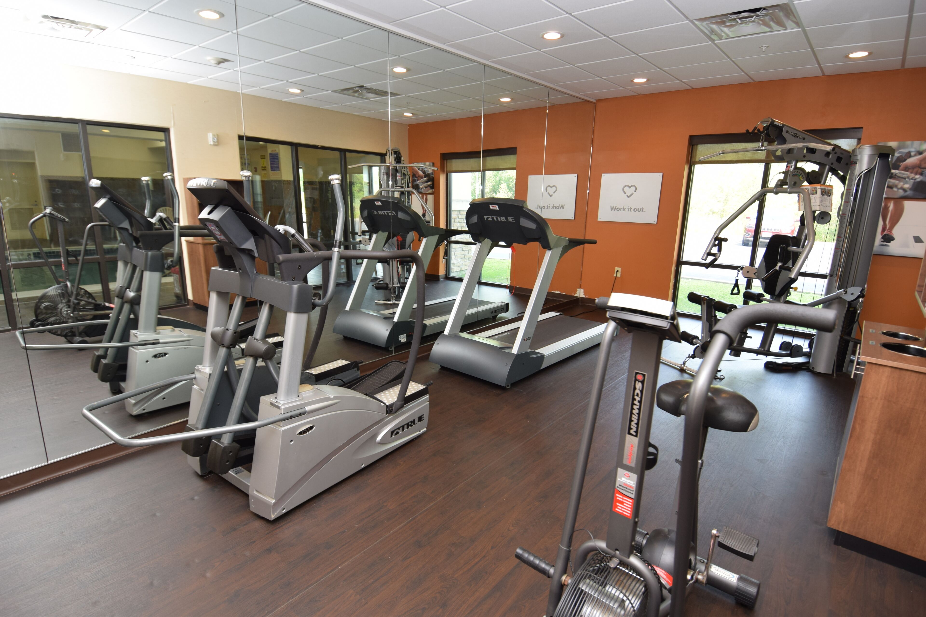 Et fitnesscenter med løbebånd, crosstrainere og styrkeudstyr.
