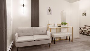 Uma sala de estar moderna com um sofá, uma mesa pequena com abajur e um espelho.