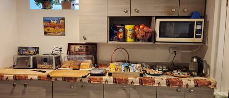 Una cocina con armarios de madera, microondas, tostadora y diversos alimentos sobre la encimera.