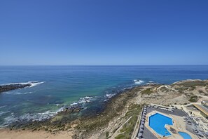 Un hotel frente al mar con piscina, acceso a la playa y vistas al océano.