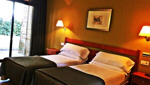 Habitación de hotel con dos camas, una ventana con cortinas, un cuadro colgado en la pared y dos lámparas de noche.
