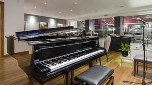 Un piano de cola en una habitación amplia con piso de madera, un banco y una decoración interior moderna.