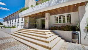 Una entrada de hotel moderna con fachada de piedra, un alero de madera y un conjunto de escalones de piedra que conducen a la entrada.