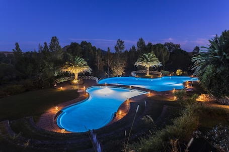 Una piscina al aire libre, sombrillas, sillones reclinables de piscina