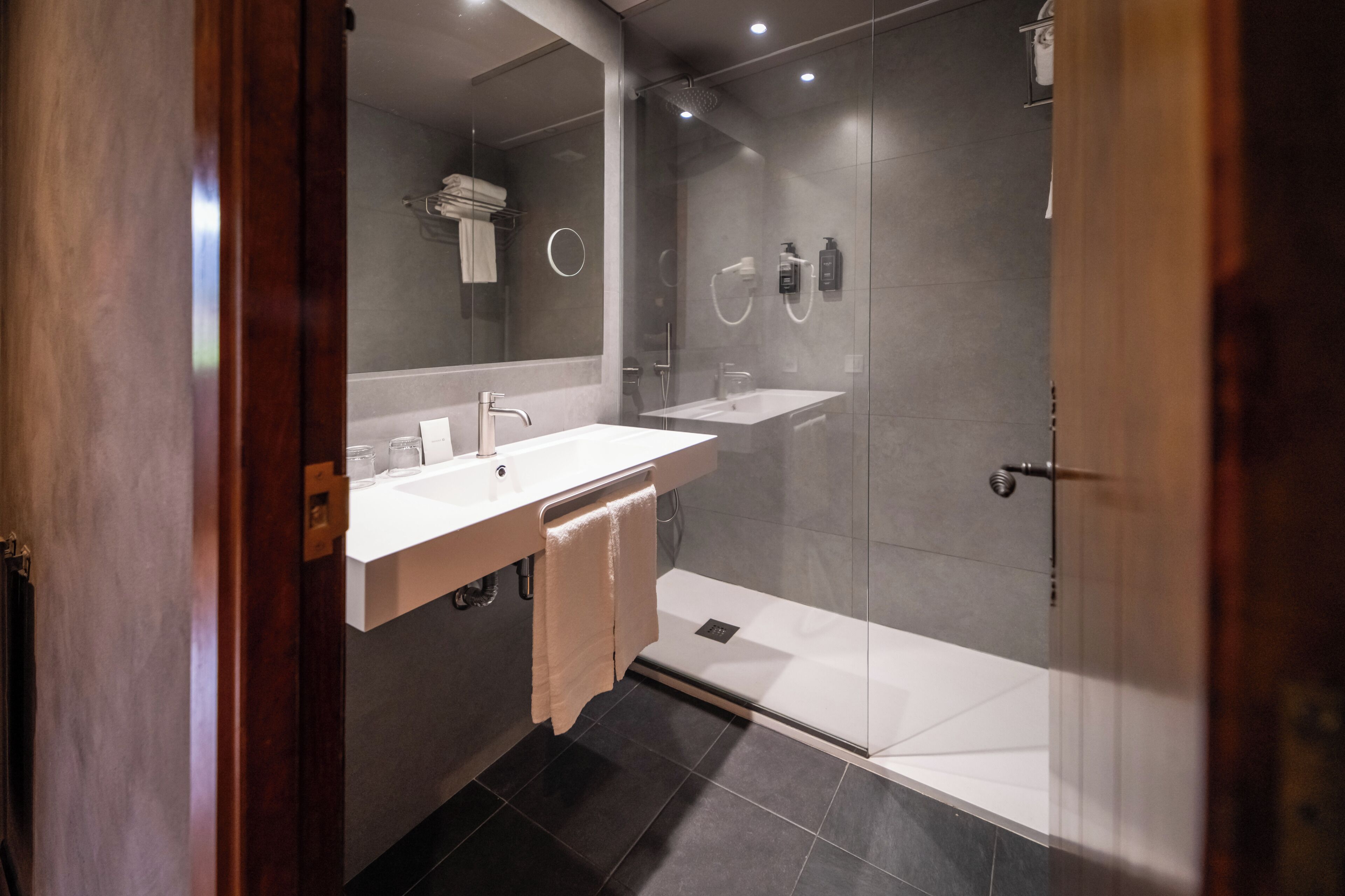 A modern bathroom with a glass shower enclosure, a vanity with a mirror, and a towel rack.