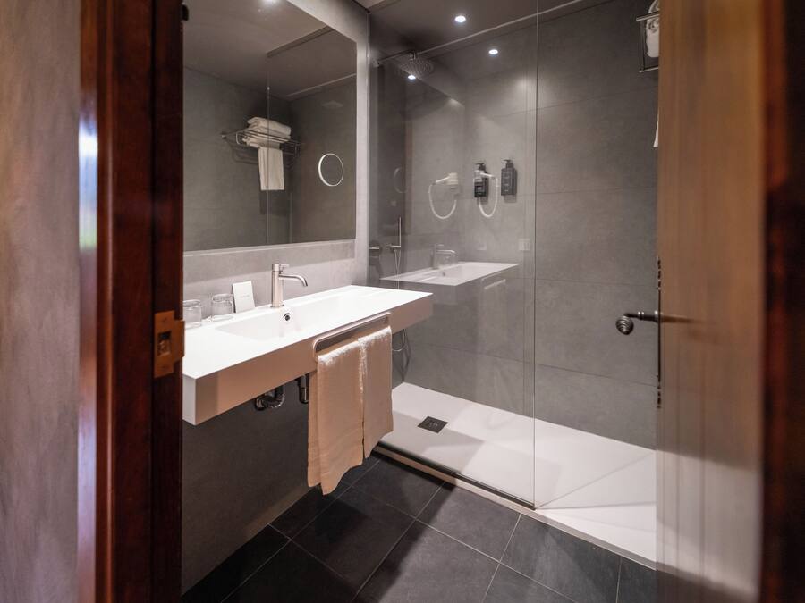 Un baño moderno con cabina de ducha de vidrio, tocador con espejo y perchero.