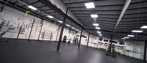 A spacious gym with a high ceiling, exposed beams, and various exercise equipment.