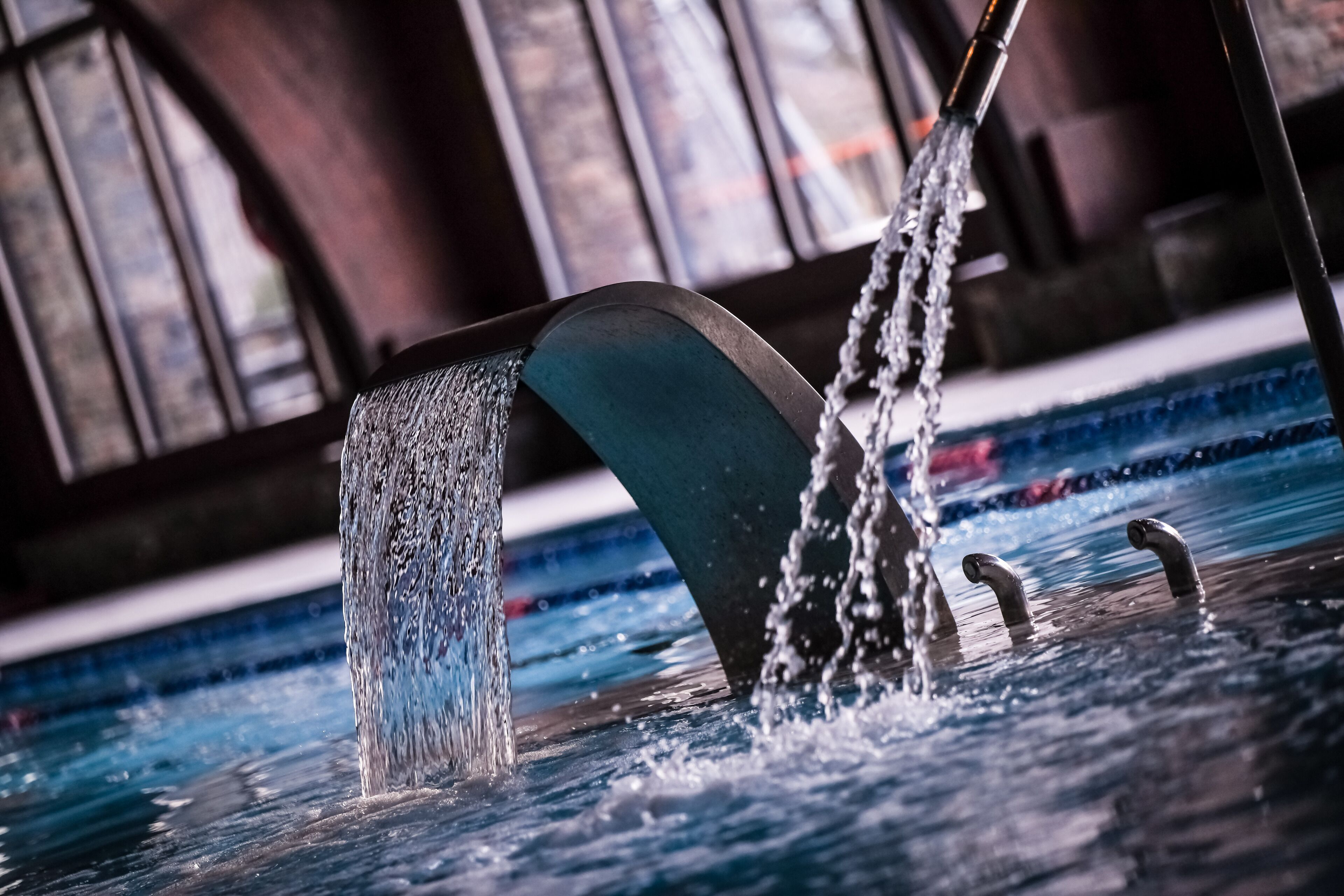 Una fuente con una estructura curva y múltiples chorros de agua en una piscina.