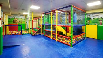 Children can play and climb in a multi-level play structure with a ball pit and safety net.