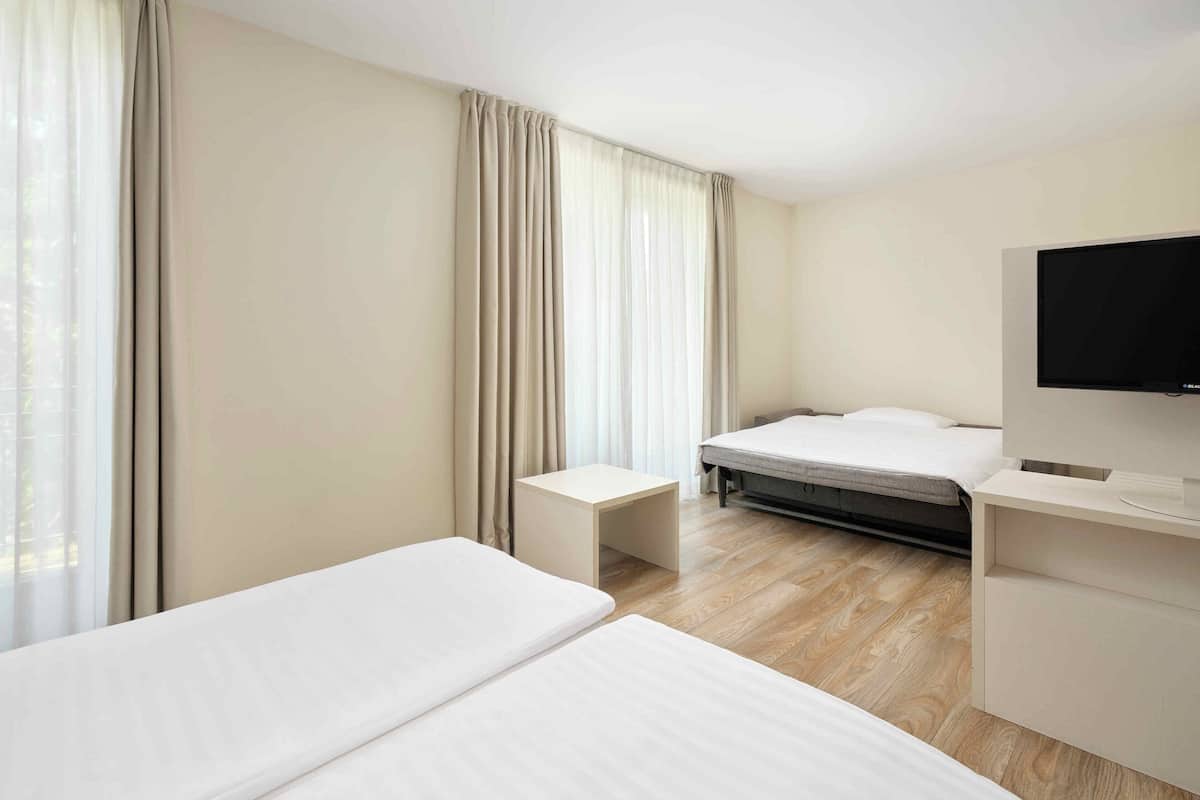 A hotel room with two beds, a TV, and a desk.