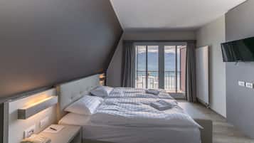 Ein modernes Hotelzimmer mit einem großen Bett, einem Nachttischtelefon und Blick auf die Berge durch das Fenster.