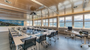 A conference room with a long table, chairs, and a projector. - Hôtel Préalpina (Chexbres)