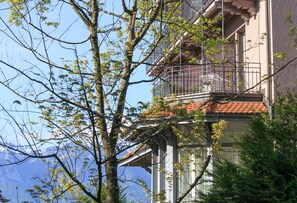 A building with a balcony, a tiled roof, and a view of mountains. - Hôtel Préalpina (Chexbres)