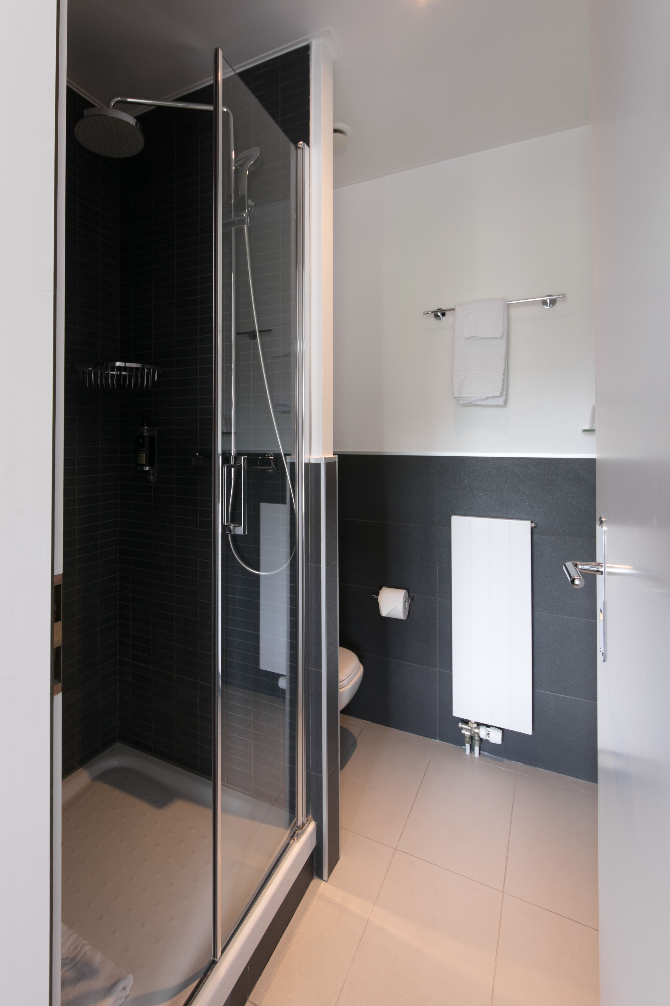 Un baño moderno con ducha de mampara de vidrio, inodoro y lavamanos.