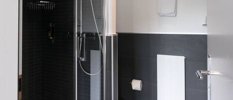 Un baño moderno con ducha de mampara de vidrio, inodoro y lavamanos.