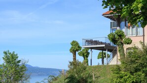 A building with a balcony overlooking a body of water and a distant landscape. - Hôtel Préalpina (Chexbres)