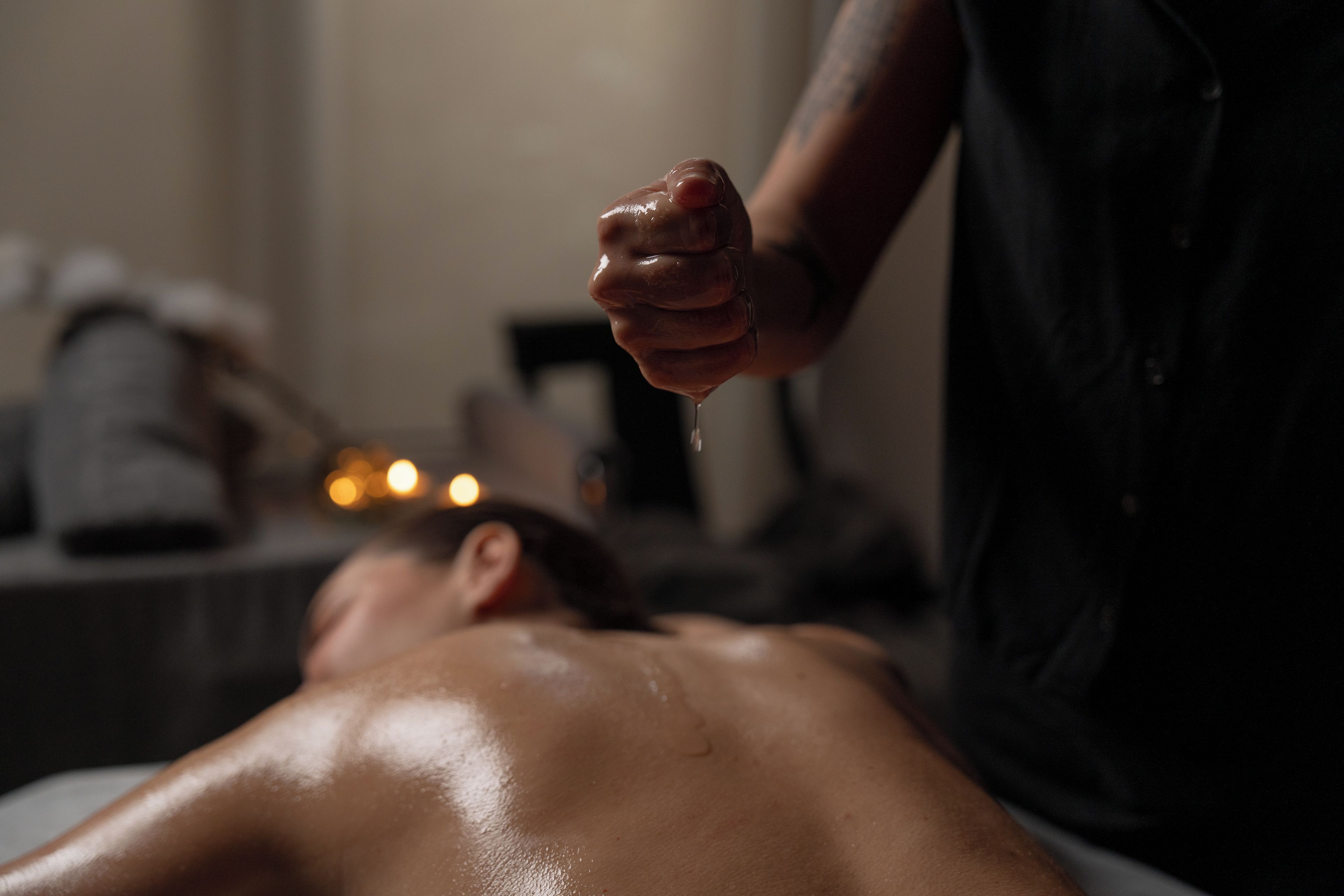 Uma pessoa recebendo massagem, com foco nas mãos e na parte superior do corpo.