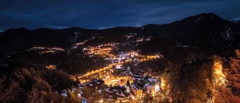 A town at night with illuminated buildings and a mountain backdrop.