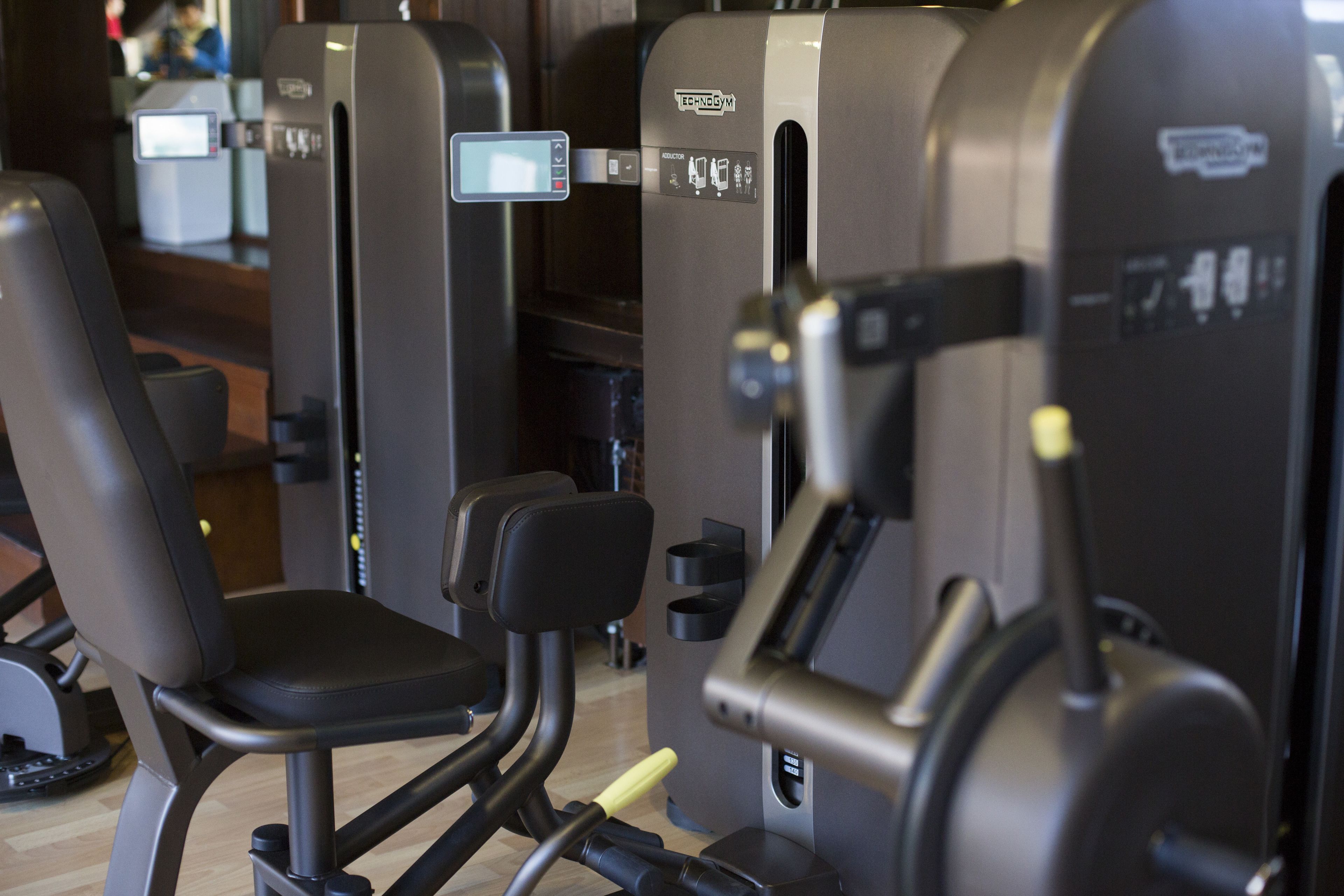 A gym with various exercise machines, including a bench press, a chest press machine, and a leg press.