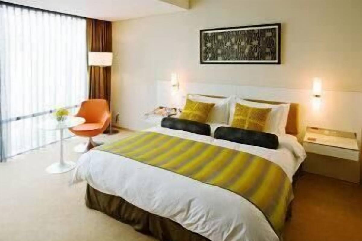 Habitación de hotel con cama, una silla, un escritorio y una ventana con cortinas.