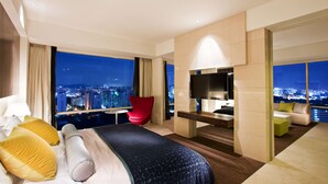 A modern hotel room with a large bed, a red chair, a TV, and a city view. - Ramada Plaza Suwon (Suwon)