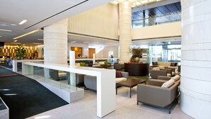 A spacious lobby with a modern design, featuring a central seating area with sofas and a coffee table, a glass railing, and a staircase leading to an upper level. - Ramada Plaza Suwon (Suwon)