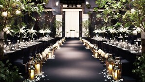A long table set for a formal event, flanked by tall, illuminated vases and greenery. - Ramada Plaza Suwon (Suwon)