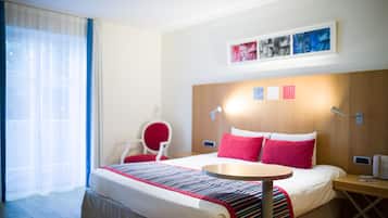 Ein Hotelzimmer mit Bett, Nachttisch, Stuhl und Schreibtisch.