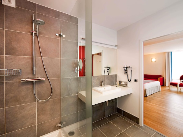A modern bathroom with a shower, sink, and mirror.