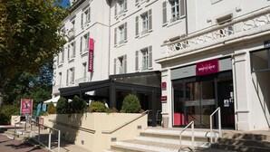 Fachada de hotel con una escalera que conduce a la entrada, un letrero que dice 'Mercure' y arquitectura clásica.