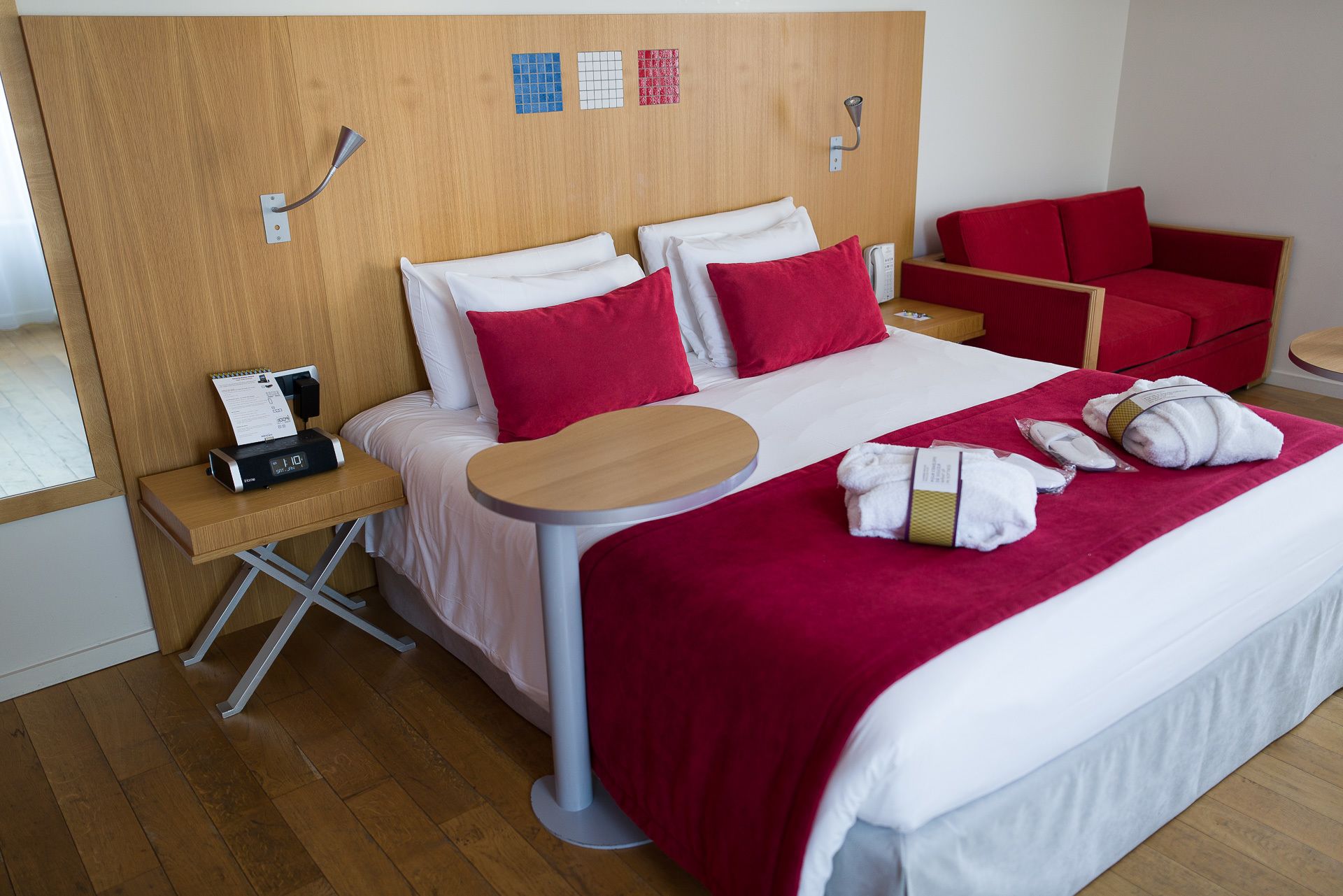 A hotel room with a bed, a desk, a chair, and a small table.