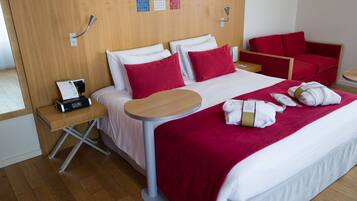 A hotel room with a bed, a desk, a chair, and a small table.