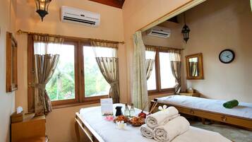 Traditional room with a wooden bed, separate sleeping area, and a small table with toiletries.