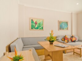 Una sala de estar moderna con un sofá gris, una mesa de centro de madera y dos cuadros en la pared.