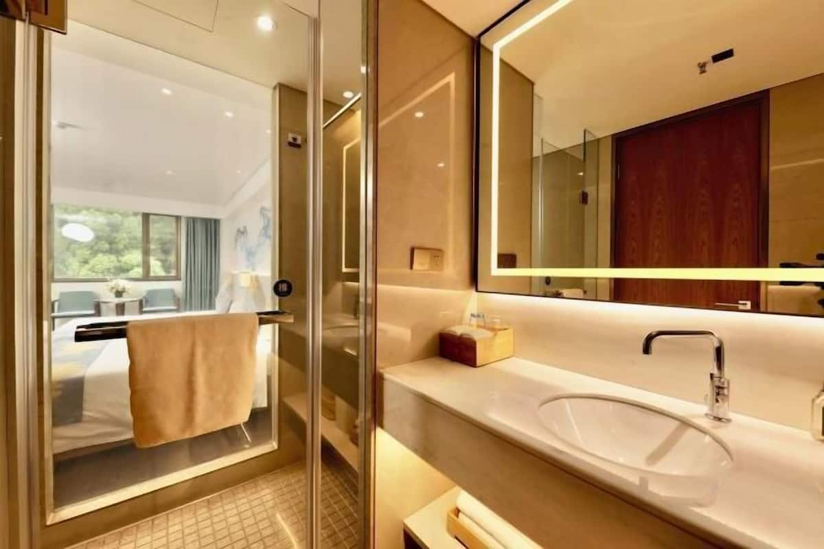 A modern bathroom with a glass shower enclosure, a large mirror, and a white sink.