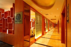 A hotel lobby with a long corridor, wooden reception desk, and a wall with a logo. - Jinling Lakeview Hotel (Wuxi)