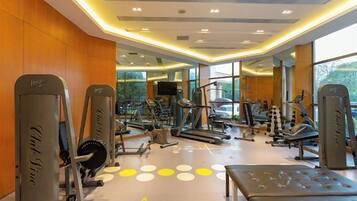 A gym with various exercise equipment, large windows, and a modern design.