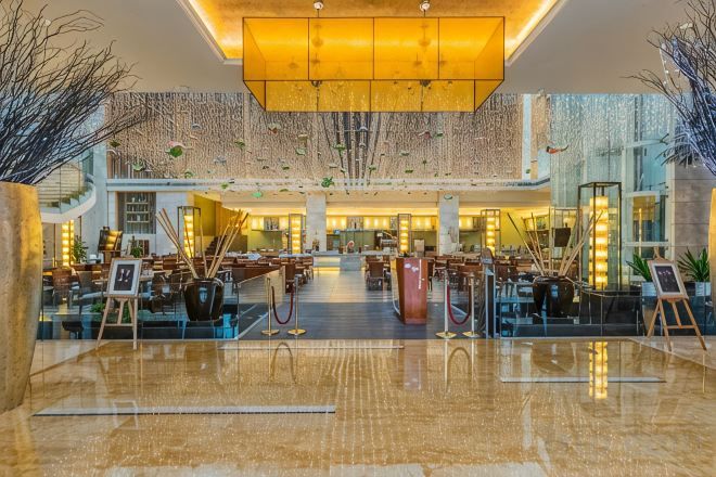 A spacious lobby with a high ceiling, a central chandelier, and a polished floor.