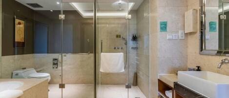 Un baño moderno con ducha de vidrio, un lavamanos grande y un espejo.