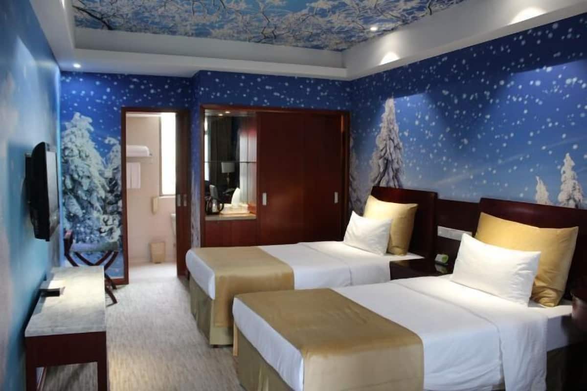 A hotel room with two beds, a desk, and a TV.