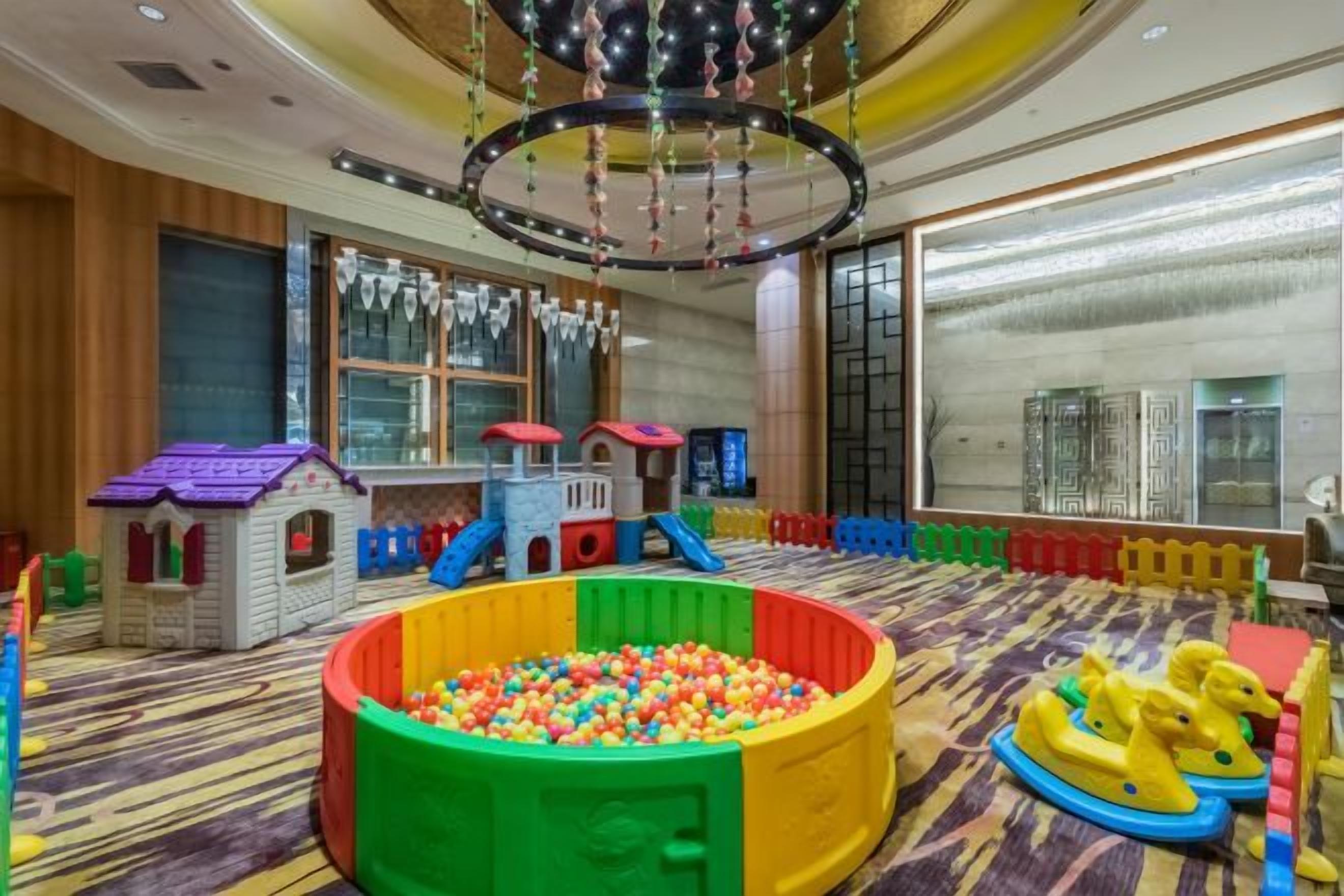 Un espace de jeux pour enfants avec une piscine à balles, des structures de jeu et un toboggan.