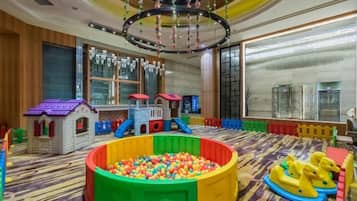 Un espace de jeux pour enfants avec une piscine à balles, des structures de jeu et un toboggan.