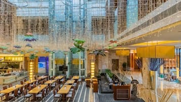 A spacious indoor area with multiple dining tables and chairs, a glass ceiling, and decorative elements.