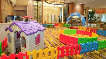 Un espace de jeux pour enfants avec une piscine à balles et une petite structure en forme de maison.