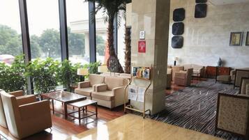 Een hotel lobby met een zithoek, een receptiebalie en een groot raam met uitzicht op de omgeving.